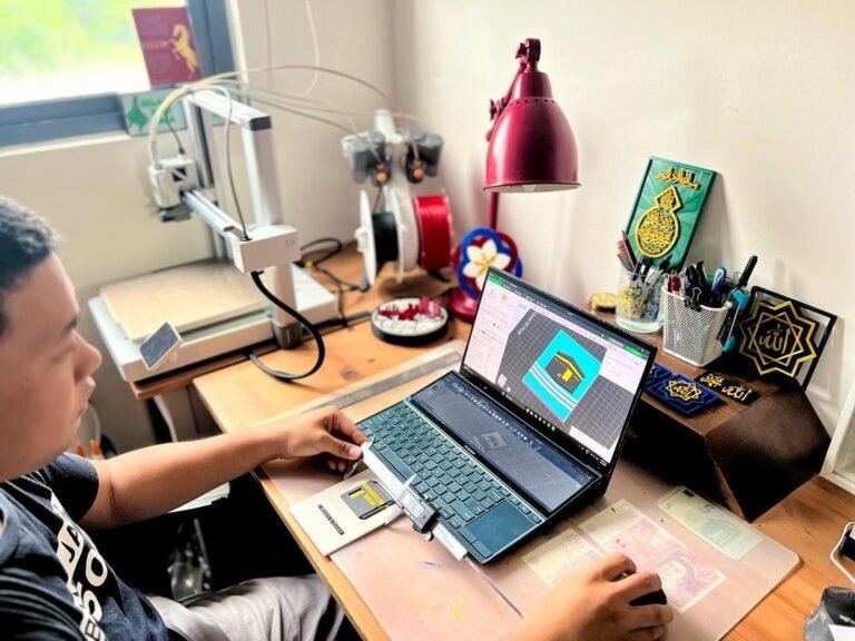 Nik Adam pengasas Tiganun sedang menggunakan laptop di ruangan kerja cetakan 3D
