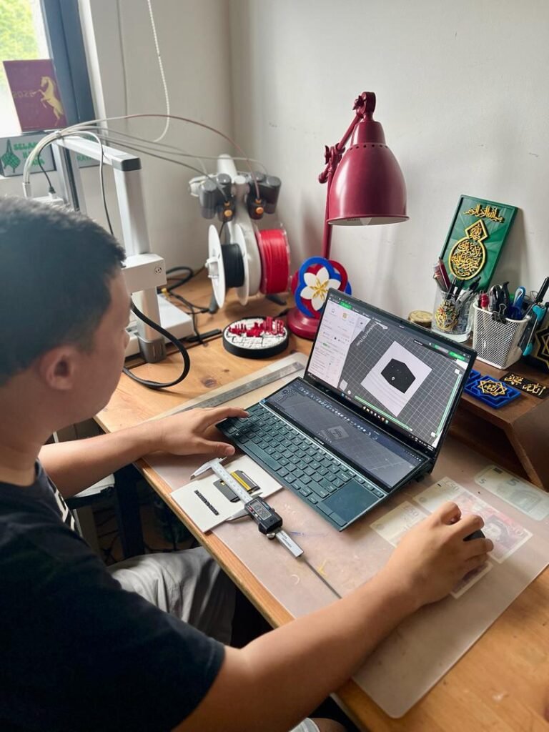 Pandangan sisi Nik Adam sedang melaraskan tetapan slicer model 3D menggunakan tetikus